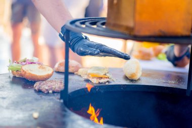 Eldivenli el hamburgerde köfte, peynir ve sebze topluyor. Hazır düzen