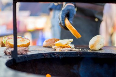 Eldivenli el hamburgerde köfte, peynir ve sebze topluyor. Hazır düzen