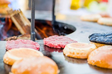 Izgarada çiğ burger köftesi. Barbeküde ateş açın.