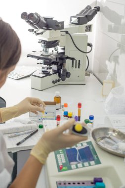 Laboratuvar asistanı, modern bir laboratuvarda analiz cihazında kan testi uygular.