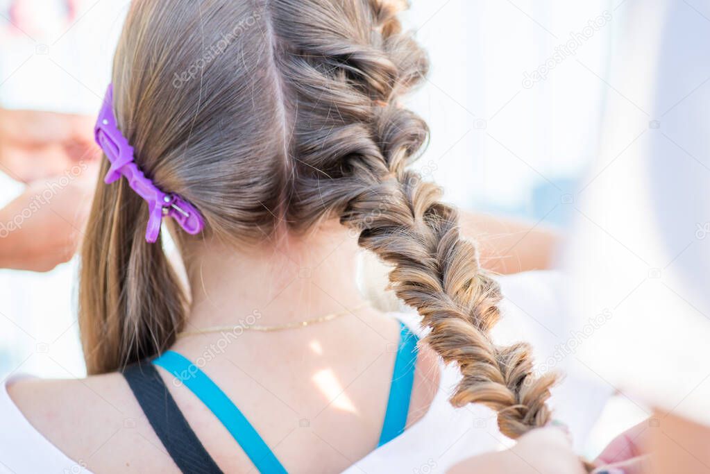 braiding braids on long hair. Hairdresser doing hairstyle in the salon