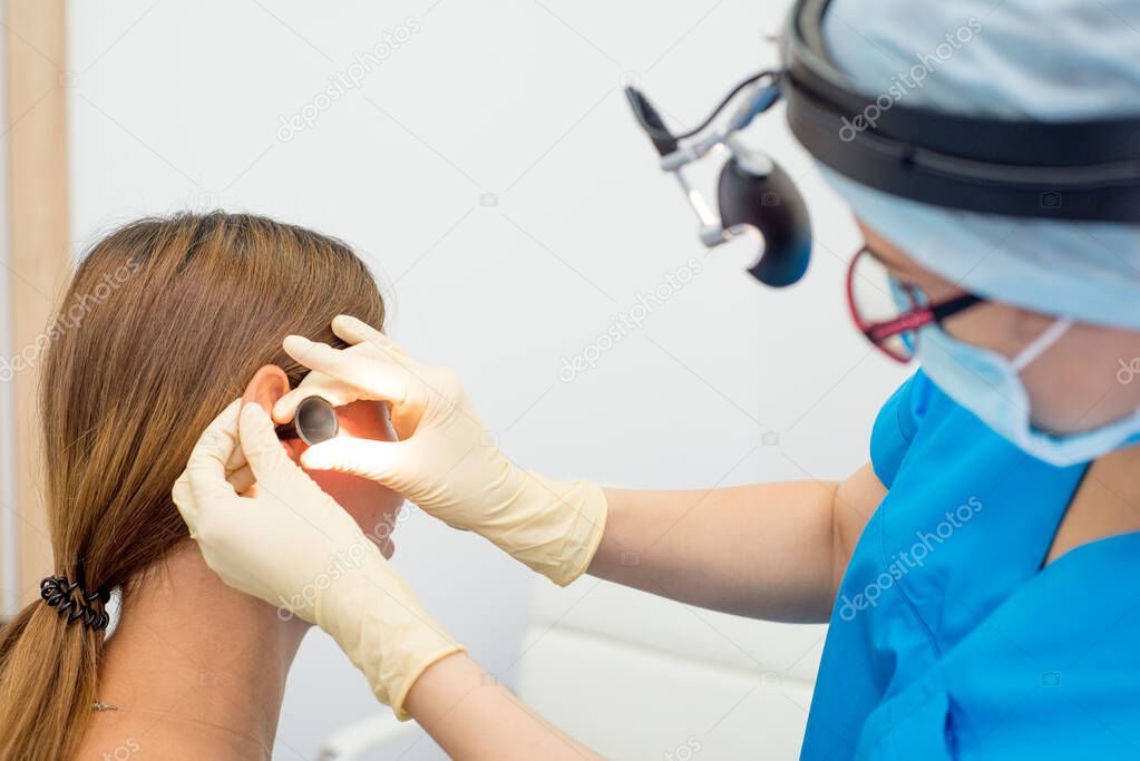 ENT doctor with tools, a mask and gloves examines the patient's ears. Otolaryngologist with he