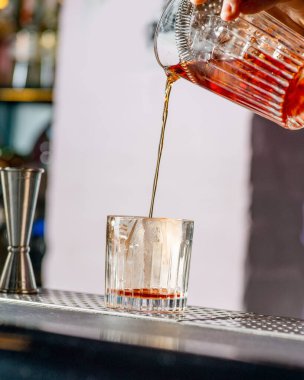 Barmen bardağa bir kokteyl doldurur.