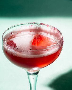 Kırmızı tropikal kokteyl, arka planda kristal şeklinde güneş ışığı ve gölgeli. Yeşil arka plan.