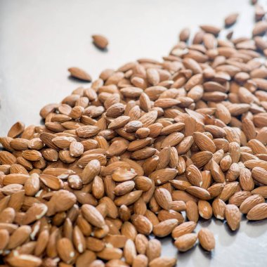 Gri metal arka planda bir sürü badem serpiştirilmiş.