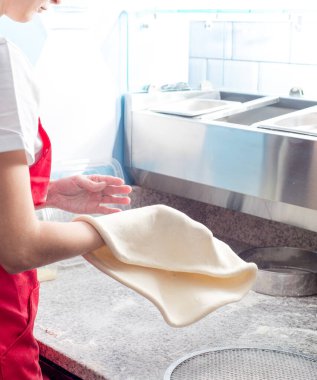 Pizzaolo döner ve pizza hamuru fırlatır. Pizza hamuru hazırlanıyor.