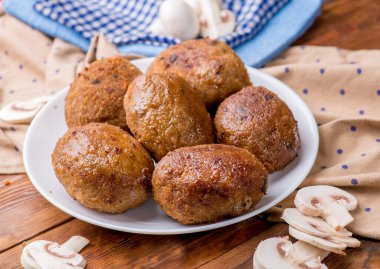 Sebze ve sebzelerin arka planında beyaz bir tabakta pirzola. Tahta masa ve ev manzarası