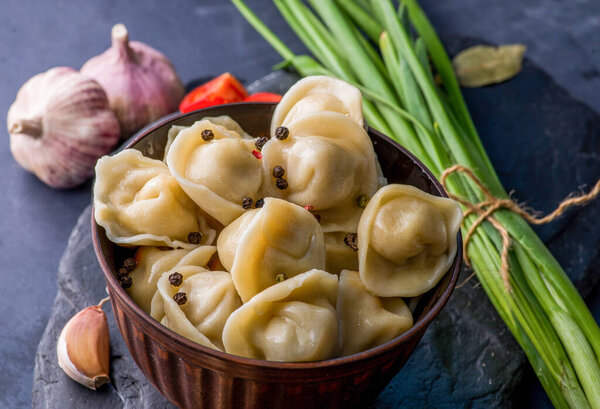 вареные пельмени с начинкой и соусом на тарелке. Пар над тарелкой