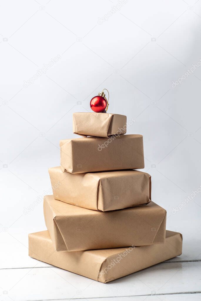 Wrapped gifts in kraft paper. Christmas tree made of gifts with a red ball