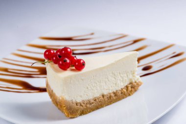 Beyaz servis tabağında kırmızı üzümlü klasik cheesecake.