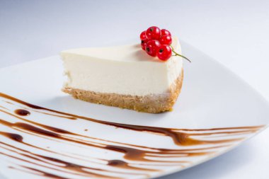 Beyaz servis tabağında kırmızı üzümlü klasik cheesecake.