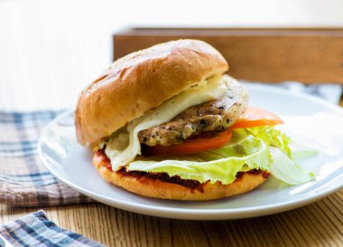 Ahşap masada servis edilen ızgara ekmekli hamburger.