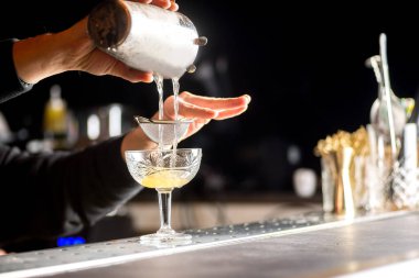 Barmen kokteyl hazırlıyor. Barmen bir kokteyl dolduruyor.