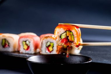 Soya sosuna batırılmış somon rulosuyla yakın plan.