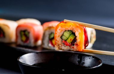 Soya sosuna batırılmış somon rulosuyla yakın plan.