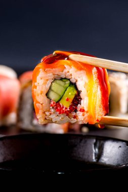 Soya sosuna batırılmış somon rulosuyla yakın plan.