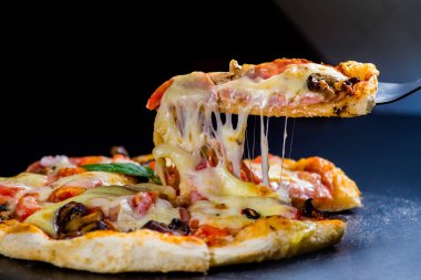 Pizza bir dilim kes. Eritilmiş peynir uzanıyor parçasındaki