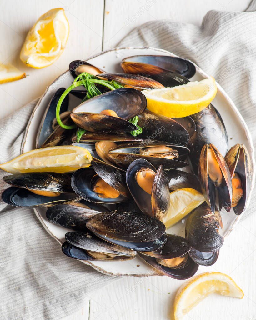 plate with boiled mussels in armor with lemon pieces