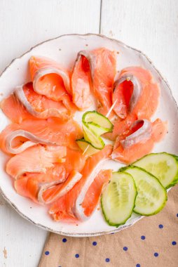 Salatalık ve yeşillikle süslenmiş somon filetosu dilimlenmiş tabak.