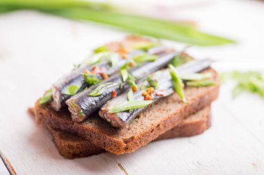 Bir parça siyah ekmeğin üzerinde baharat olan küçük bir balık.