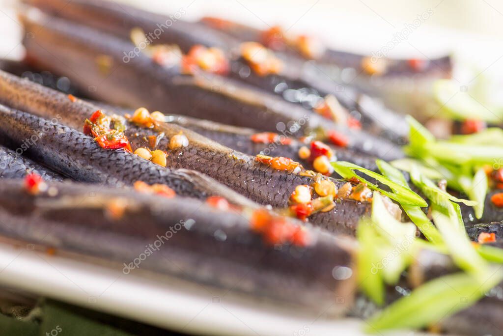 sprat with spices and herbs on the background of a served plate