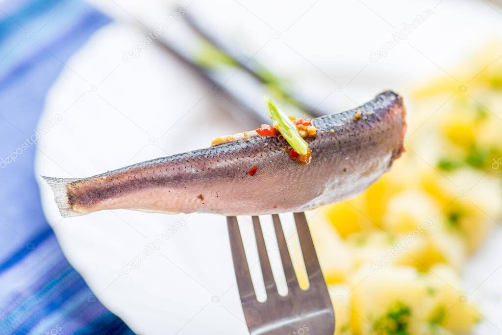 Small fish of sprat with spices on a fork