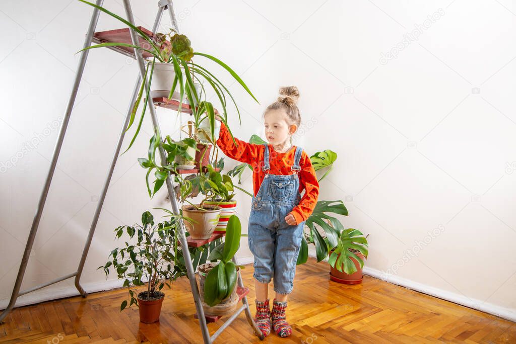 Child in denim overalls watering from a watering ca