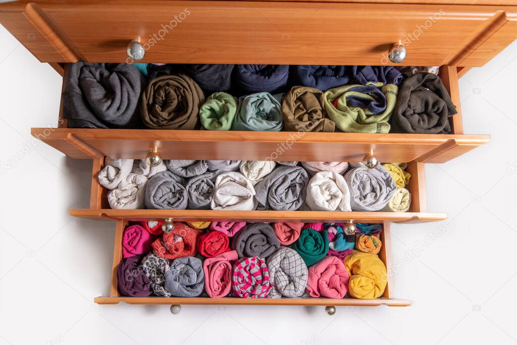 Open chest drawers with  vertical storaged twisting clothes. View from above. Storage of clothes in the wardrobe. Japanese method