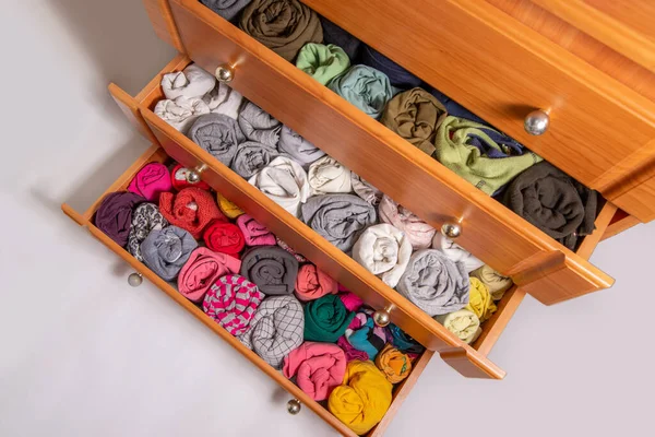 Open chest drawers with  vertical storaged twisting clothes. View from above. Storage of clothes in the wardrobe. Japanese method