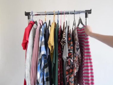 Elbiseleri gardıroptaki askıya as. Beyaz arka plan. Sürdürülebilir moda kavramı