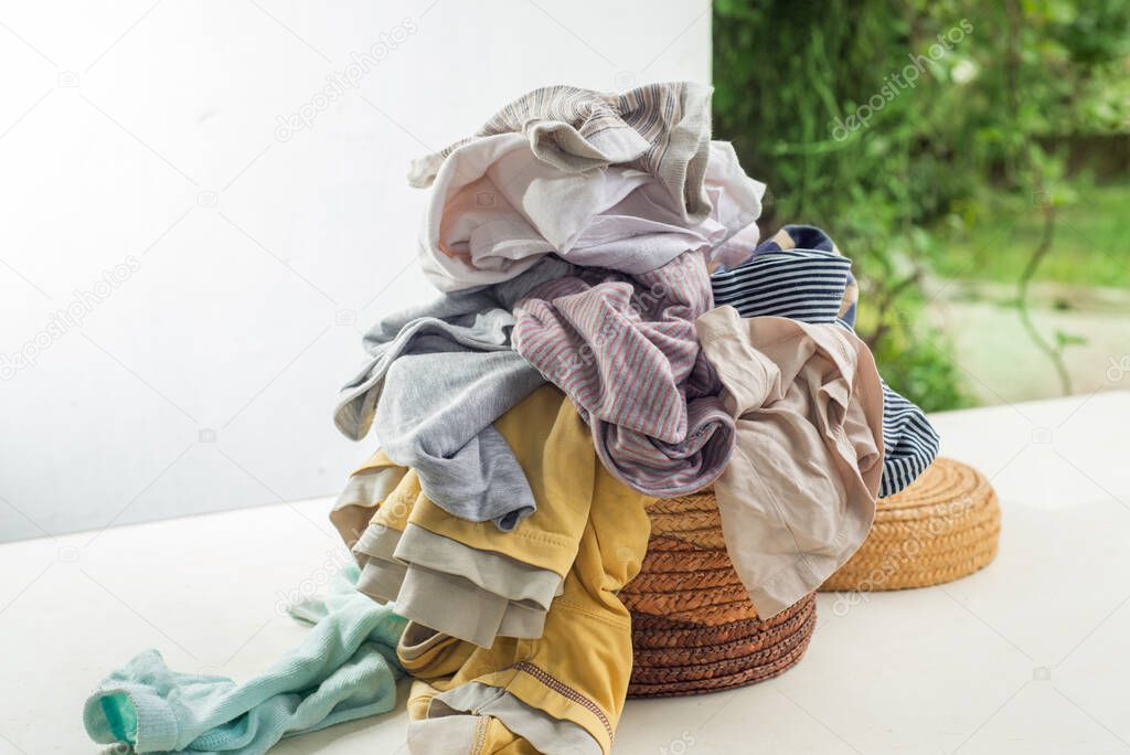 Used clothes in a pile on a laundry basket. Sorting and cleaning second-hand. Preparing for washing. Copy space on white background