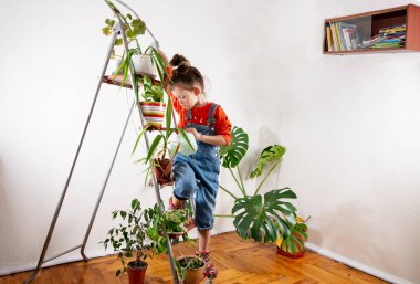 Kot pantolonlu çocuk sulandırıcı bardaktan su içiyor.