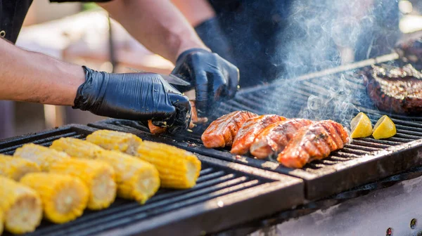 烹调烤鱼 手套手把鱼片放在烤架上 烤鲑鱼在炭烤架上 全家度假期间在后院野餐 — 图库照片