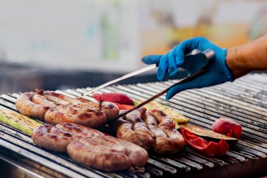 Barbekü sosisleri ateşte kızartılır. Kömür ızgarasında ızgara sosis. Aile tatili sırasında arka bahçede piknik. Barbekü yemeği.