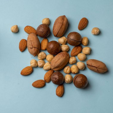 Various nuts scattered on a light background. Almonds, hazelnuts, pecans, macadamia in a pile top view. The concept of healthy food and snacking