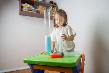 Attentive child makes a volcano from soda and vinegar. A chemise experience at home. Back to school. Homeschooling and distance education