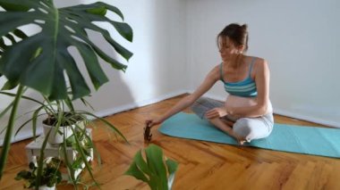 Pregnant young caucasian woman doing yoga by online workout. Pregnant woman in a pose for meditation and breathing exercises.  Yoga for pregnant women online. Online workouts for pregnant women. 