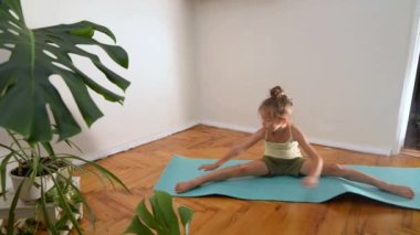 Little girl doing yoga at home. Children's yoga and breathing exercises. Children's sports and exercises at home