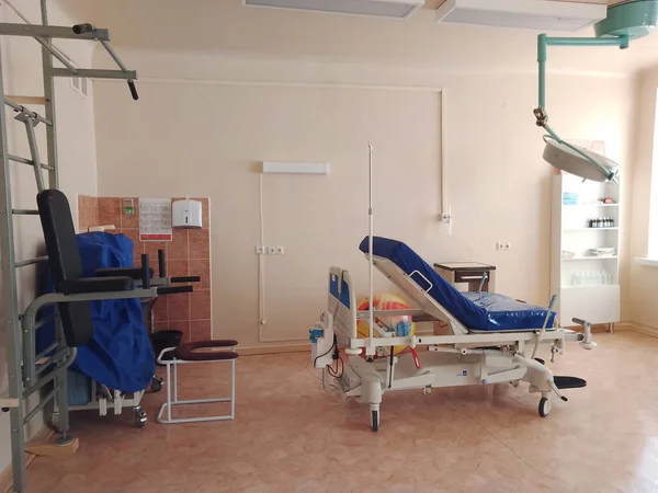 Maternity room with a gynecological gurney for childbirth, wall bars and medical equipment to facilitate childbirth. Delivery room.  Modern ward for childbirth. Maternity hospital inside