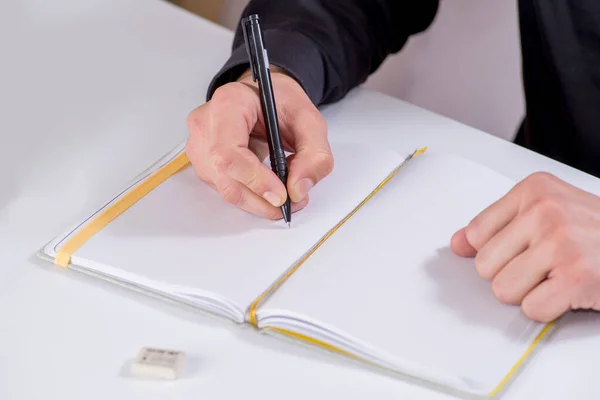 person makes notes and drawings in a notebook with a pen