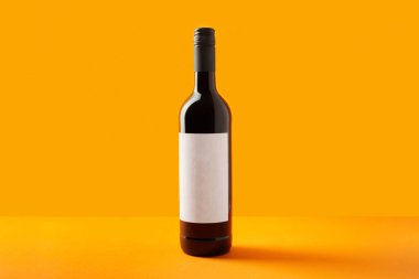 Boş etiketli şarap şişesi. Fotokopi alanı olan yaratıcı arka planda kırmızı şarap