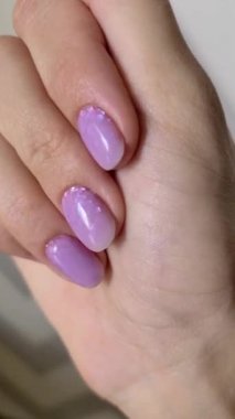 Gri arka planda modaya uygun lavanta manikürlü kadın eli olan dikey video. Tırnak tasarım eğilimleri