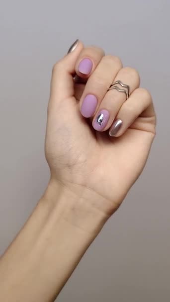 Vertical video with womans hand with trendy fashionable lavender manicure on gray background. Nail design trends — Stock Video