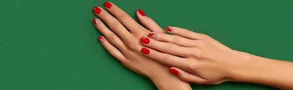 女人的手，绿色背景上有时髦的圣诞红指甲 — 图库照片