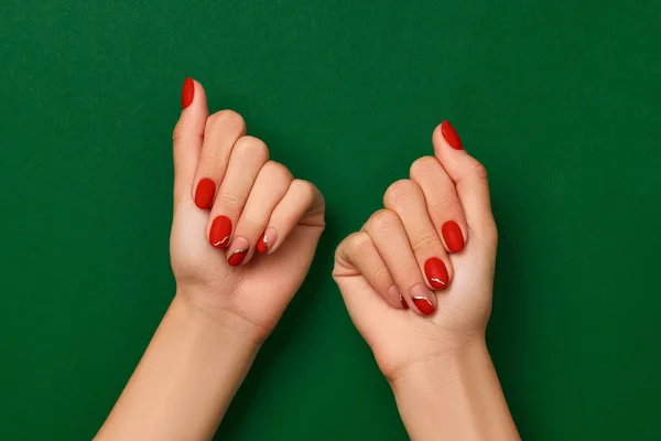 Nők kéz divatos karácsonyi piros manikűr zöld háttér — Stock Fotó