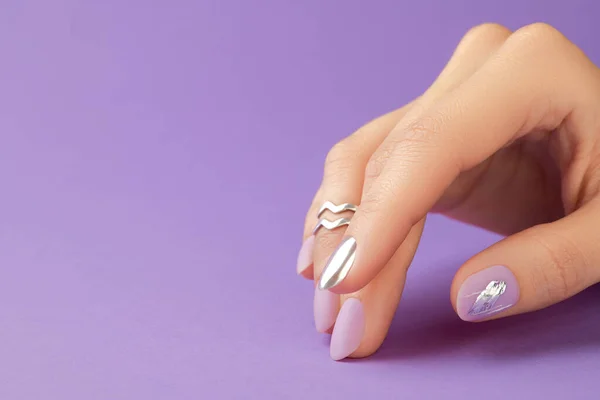 Närbild kvinnors hand med matt lavendel nagel design på lila bakgrund. Manikyr, pedikyr skönhetssalong — Stockfoto