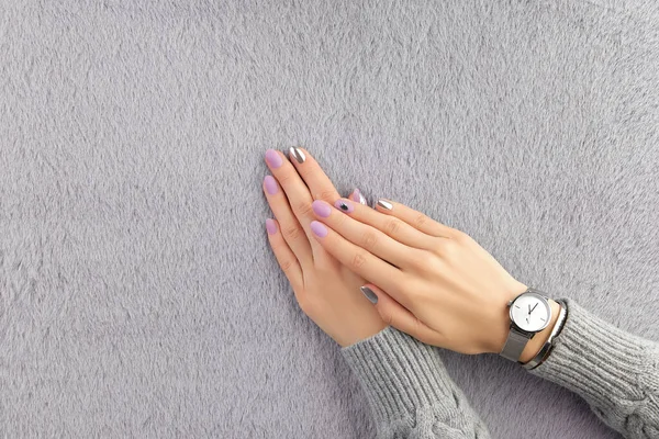 Belle mani da donna curate con il design delle unghie di lavanda opaca su sfondo grigio peloso. Manicure, pedicure concetto di salone di bellezza — Foto Stock