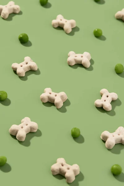 Muster mit trockenem Hundefutter und Erbsen auf grünem Hintergrund. Gesunde vegane Ernährung in Knochenform — Stockfoto