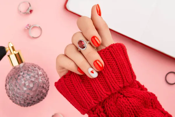Manicura de la mano de las mujeres en suéter rojo de lana caliente. Diseño de uñas de día de San Valentín de moda —  Fotos de Stock