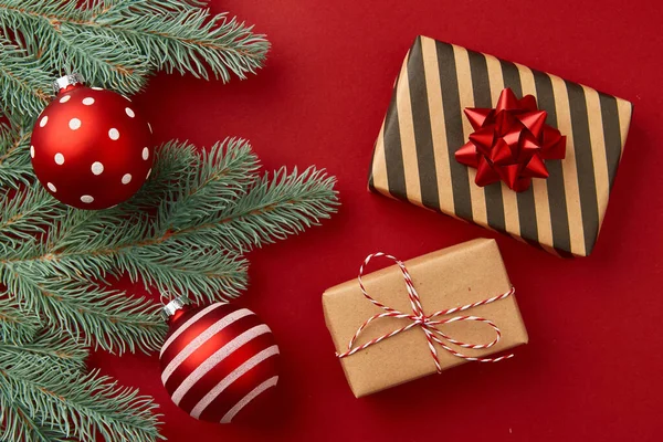 Composición navideña. Regalos ramas de árbol de Navidad y adornos sobre fondo rojo — Foto de Stock